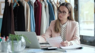 Dizüstü bilgisayarla çalışan konsantre moda tasarımcılarının videosu ve dikiş atölyesinde yeni koleksiyonların karar verme paleti.