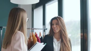 İki moda tasarımcısının dikiş atölyesinde kahve içerken ara verdiklerini gösteren bir video..