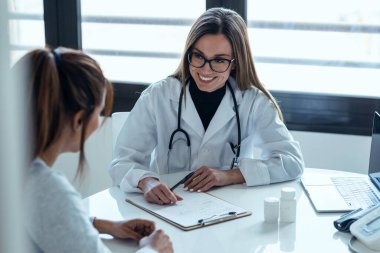 Konsültasyonda hastaya tıbbi tedaviyi açıklarken güzel bir kadın doktorun konuşması..