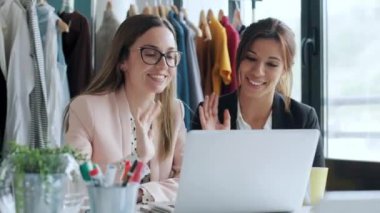 Dikiş atölyesindeki kameraya bakarken el sallayan iki güzel kadının videosu..