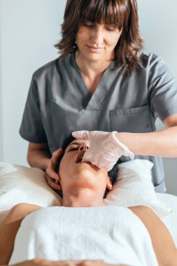 Reiki bir fizyoterapi odasında hastayı iyileştirirken genç fizyoterapistin boyun ve yüz tedavisi uygulaması.. 