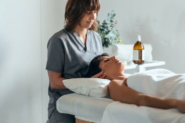Reiki bir fizyoterapi odasında hastayı iyileştirirken genç fizyoterapistin boyun ve yüz tedavisi uygulaması.. 