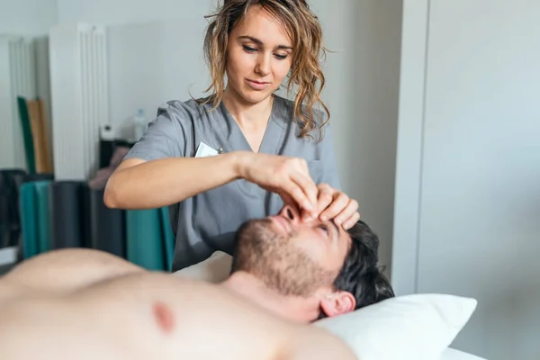 理学療法室で患者に顔の治療を行う若い理学療法士のショット リハビリテーション 医療マッサージ 手動治療の概念 — ストック写真