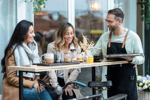 Shot Handsome Waiter Serving Toast Brunch Two Modern Girls Sitting — Foto Stock