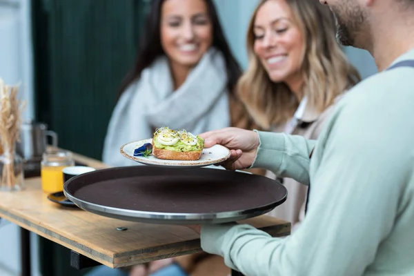 Shot Close Waiter Serving Toast Brunch Two Modern Girls Sitting — Foto Stock
