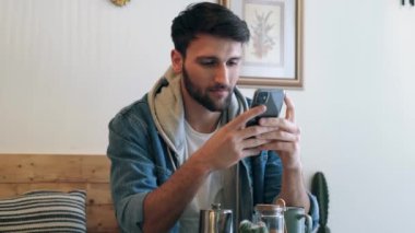 Yakışıklı bir gencin akıllı telefonuyla eko barda kahve içerken videosu..