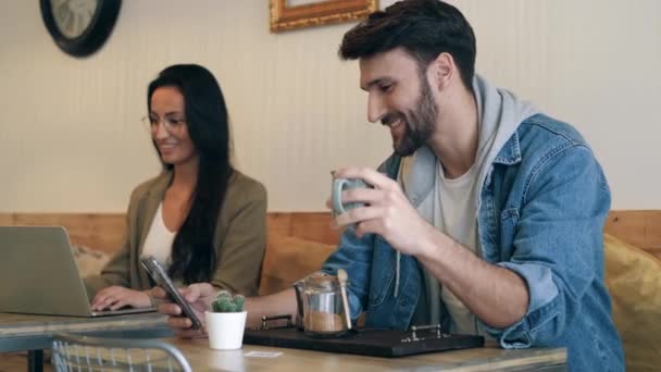 Vídeo Jovem Bonito Usando Seu Smartphone Enquanto Bebe Uma Xícara — Vídeo de Stock