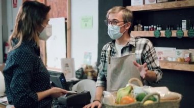 Video of  pretty young woman shopping while the seller advises on her purchases of organic food in a grocery store.