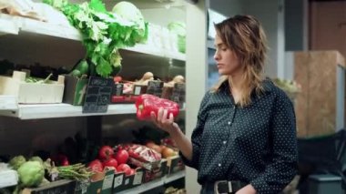 Markette raftan ürünleri alırken alışveriş arabasıyla yürüyen güzel bir kadının videosu.