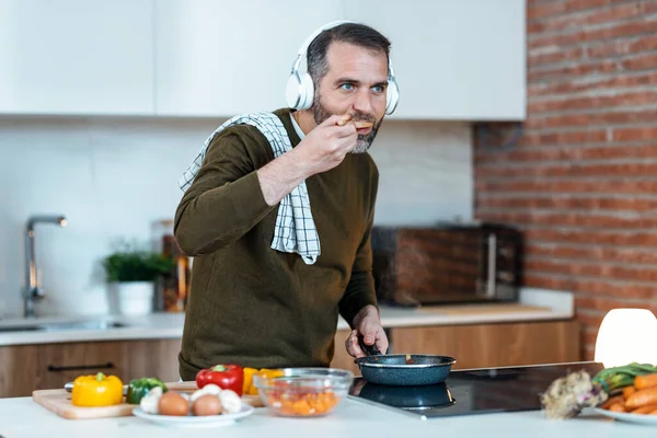 Shot Handsome Mature Man Tasting Food Preparing While Listening Music — Foto Stock