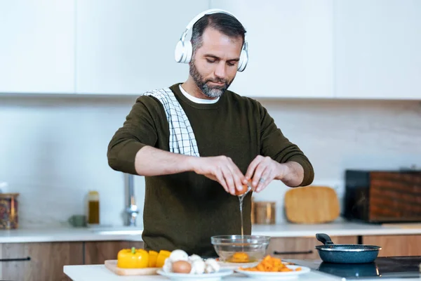 Shot Handsome Mature Man Preparing Omelette While Listening Music Headphones — Fotografia de Stock