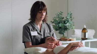 Reiki 'nin bir fizyoterapi odasında hastayı iyileştirdiği kadın fizyoterapistin boyun ve yüz tedavisi videosu.. 