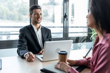 Shot of smart business people working together with laptop while talking in a modern startup.