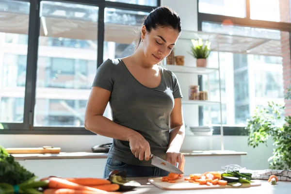 健康な若い女性新鮮な野菜を切り 自宅の台所でレシピをデジタル タブレットを使用してのショット — ストック写真
