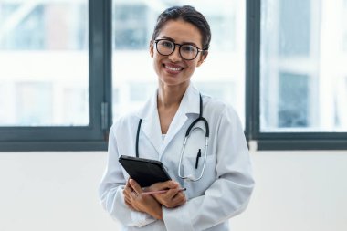 Kadın doktorun muayenede dikilirken dijital tabletini kullanması..