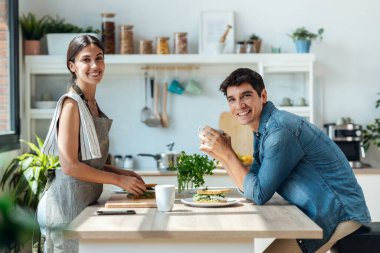 Shot of happy young couple enjoying breakfast while talking in the kitchen at home.