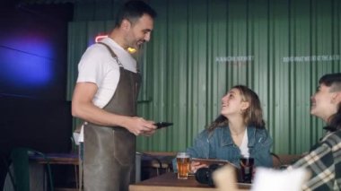 Yakışıklı garsonun dijital tablet bilgisayardaki uygulamasını kullanarak iki kızın bir restoranda yemek siparişi verirken videosu.