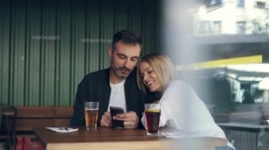 Garson restoranda patates servis ederken sevimli bir çiftin cep telefonu kullanışının videosu.