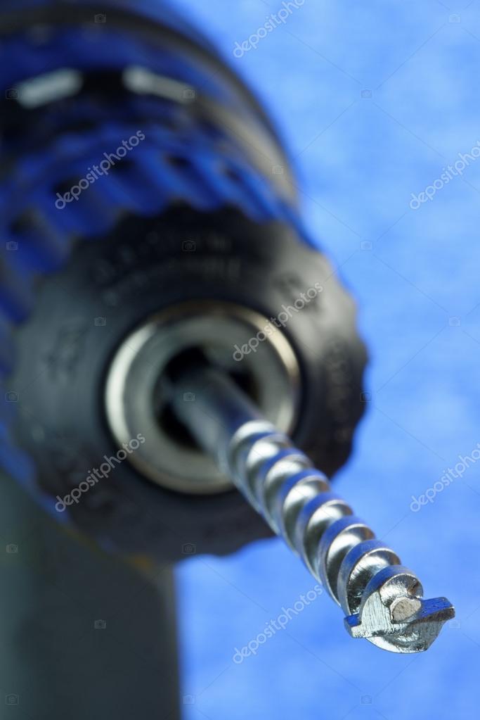 Electric drill and bit in close-up with shallow depth of field. 36 mp image against blue. Logos removed