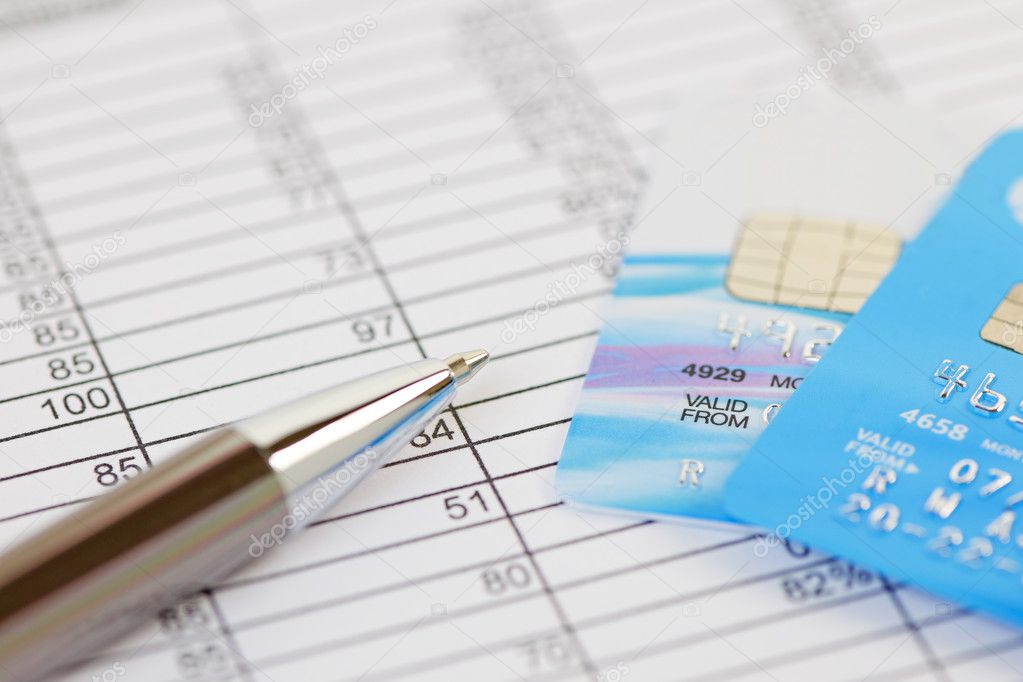 Pen and credit cards on a spreadsheet. Shallow depth of field with logos removed