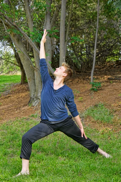 El hombre realiza una postura de yoga de guerrero inverso en el parque — Foto de Stock