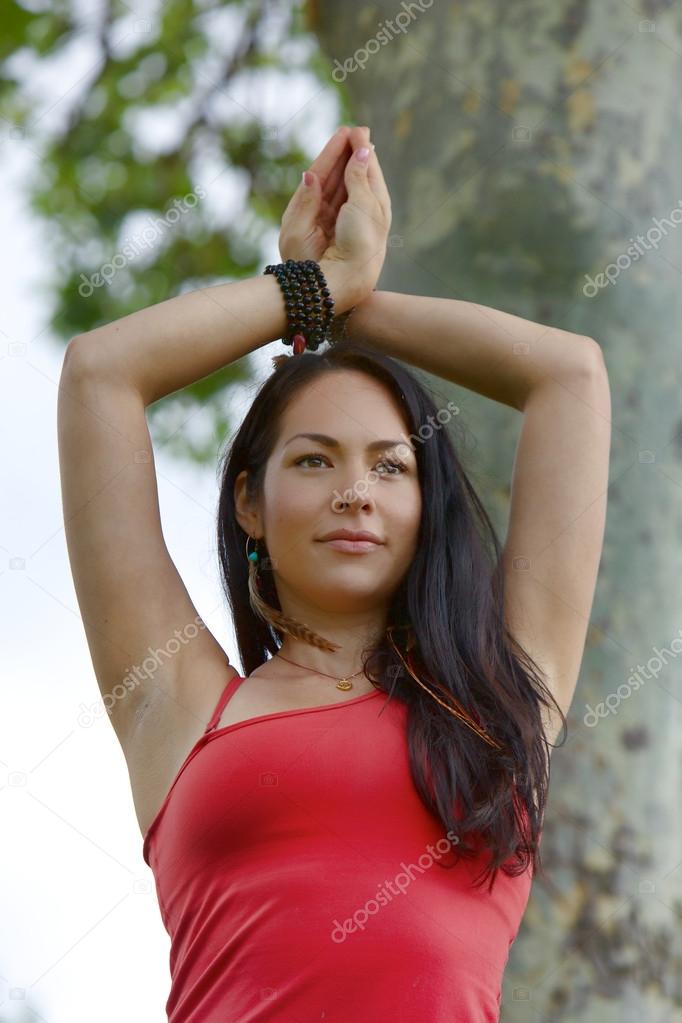 Female Yogi stands with hands crossed above her head