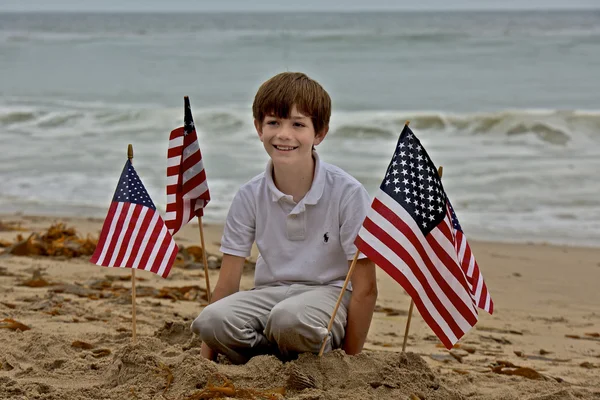 Young Boy Sits Among American Flags Planted in Sand — Stock Photo, Image