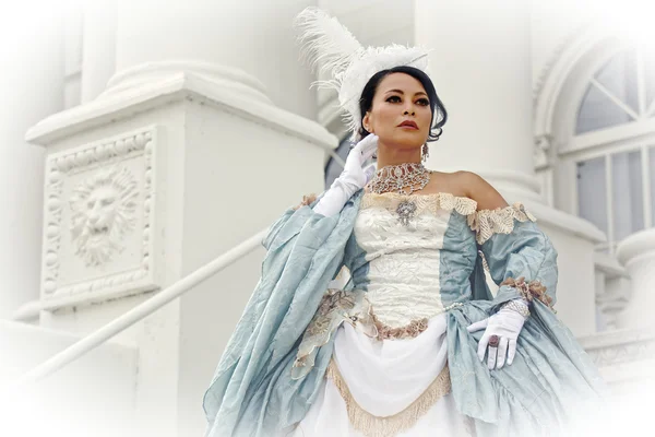 Asian Woman in Old Fashioned Style Dress in Front of Ornate White Architecture Stock Image