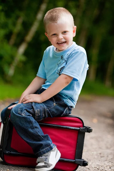 Kleine jongen zittend op zijn koffer — Stockfoto