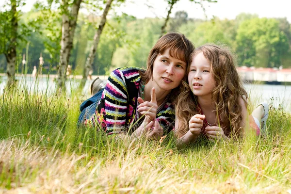 Mor och dotter kopplar av i gräset — Stockfoto