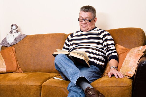 Senior reading his book on the couch