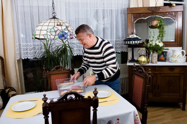 Grandfather is setting the table for breakfast — Stock Photo, Image