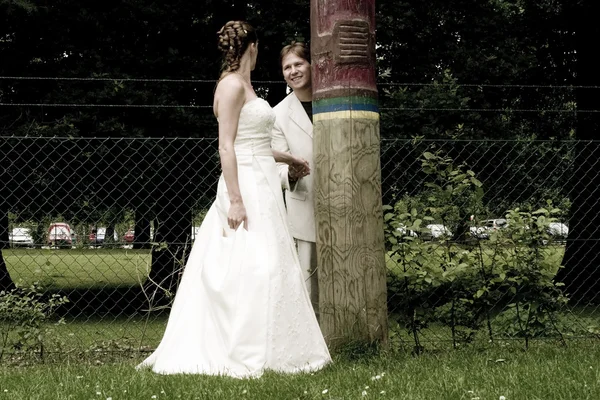 Groom and bride playing hide and seek with a totem — Stock Photo, Image