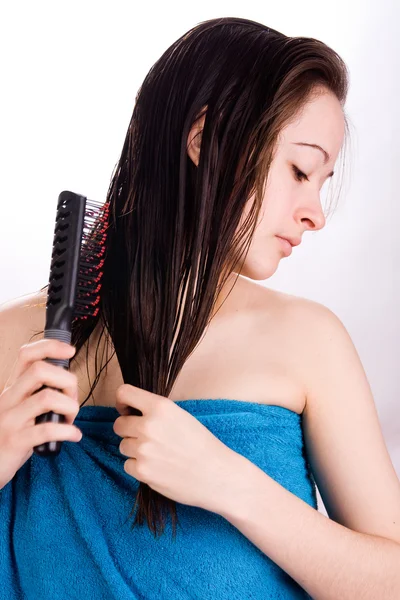 Mulher está escovando o cabelo e olhando para baixo — Fotografia de Stock