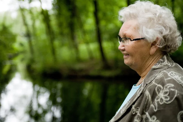 Grandmother standing near a stream — Stock Photo, Image
