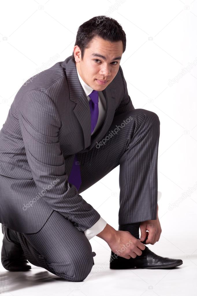 Strong young indonesian man in a suit tying his shoes