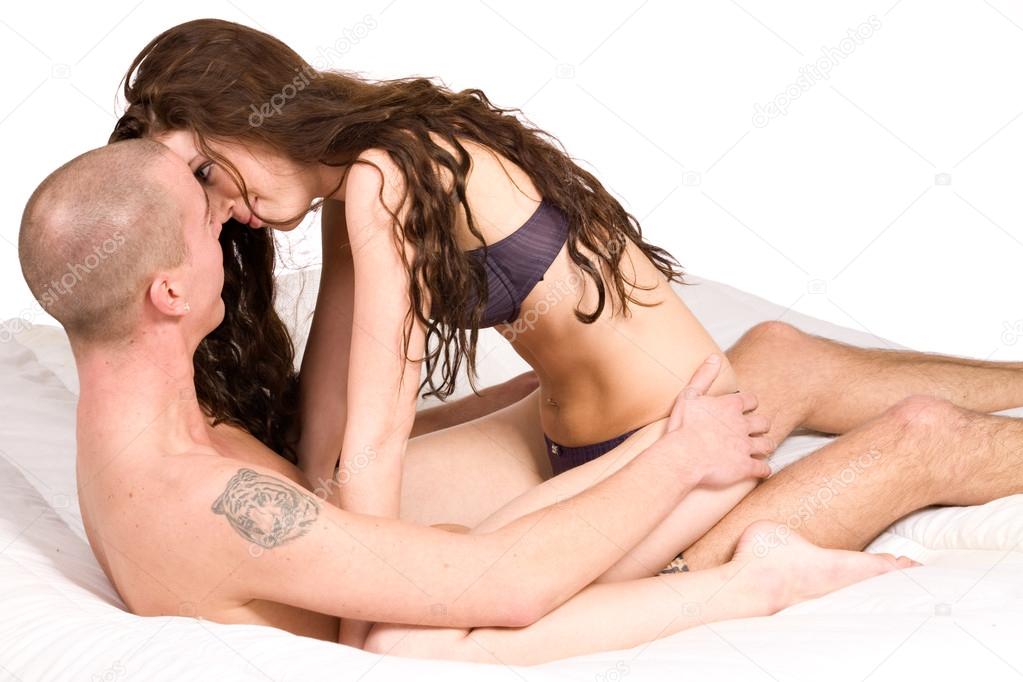Young couple sitting up in bed touching