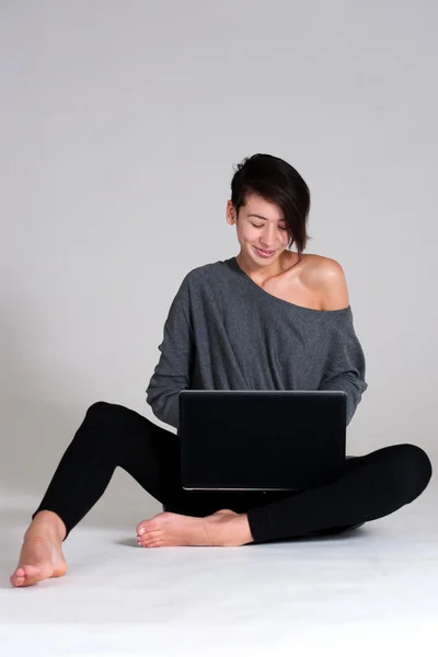 Mujer joven en el suelo con portátil — Foto de Stock