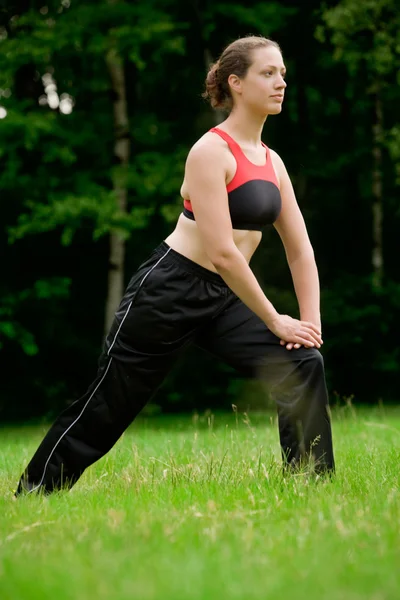 Practising yoga in a green field with trees — Stock Photo, Image