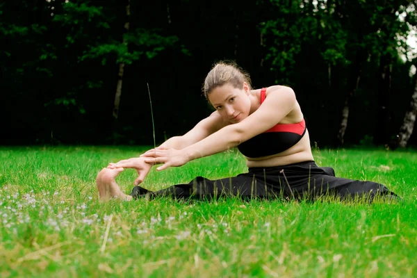 Pratiquer le yoga dans un champ vert avec des arbres — Photo