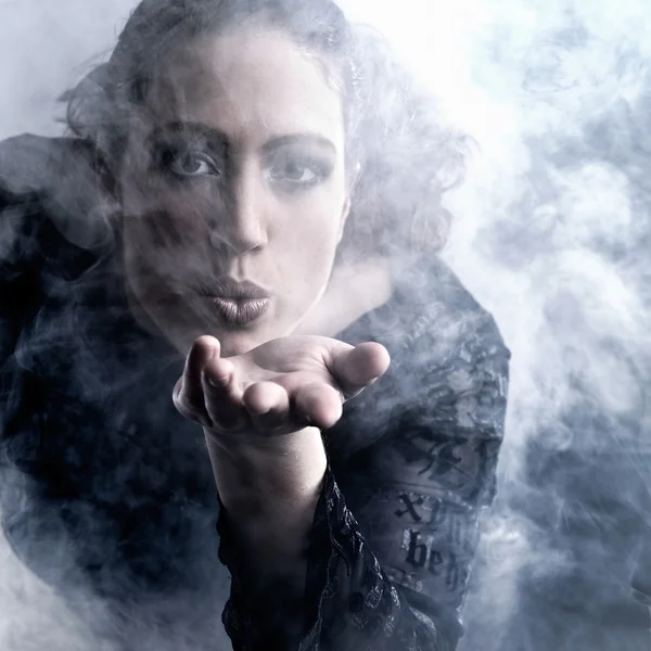 Donna con lunghi capelli ricci soffiando fumo — Foto Stock