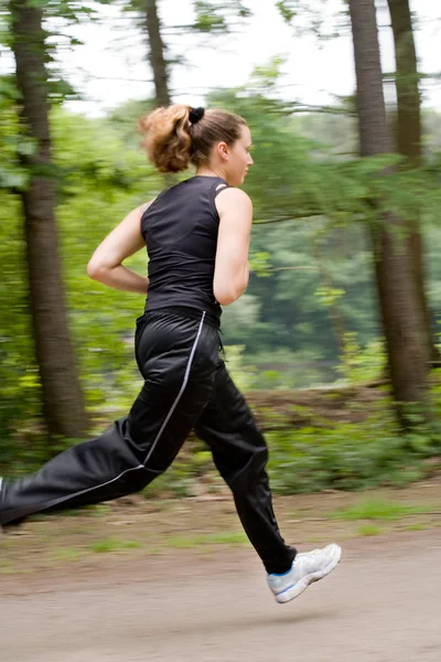 Спортивная молодая женщина, бегущая по лесной дороге — стоковое фото