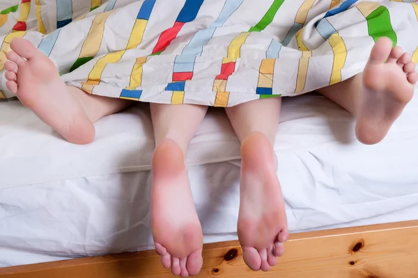 4 pieds couchés les uns avec les autres au lit — Photo