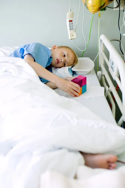 Chory chłopiec w szpitalnym łóżku z jego zabawka — Zdjęcie stockowe