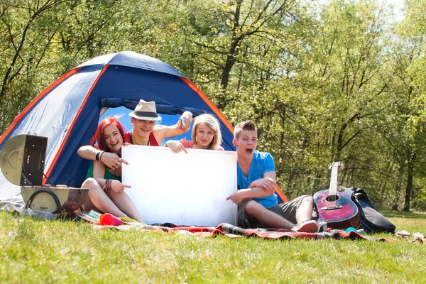 Teenagers on a camping with an empty sign board — Stock Photo, Image