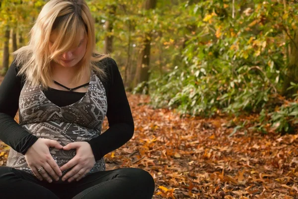 Gravid kvinna med ett hjärta fartyg i skogen — Stockfoto