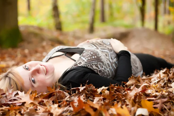 Mujer embarazada sonriente en el bosque — Foto de Stock