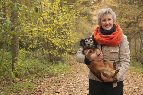 Midden leeftijd vrouw is het dragen van de hond — Stockfoto