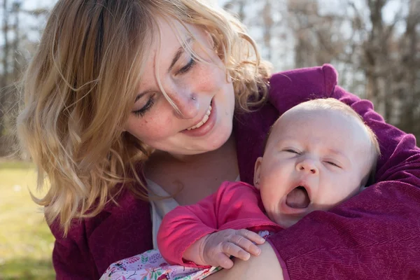 Baby is yawning in mothers arms — Stock Photo, Image