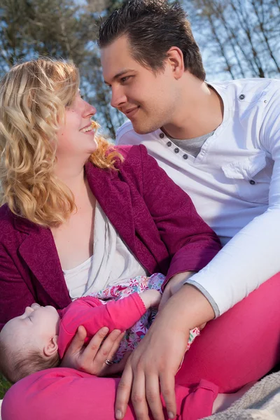 Smiling couple and their sleeping baby girl — Stock Photo, Image